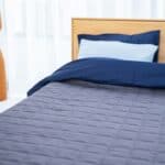Cozy bed with navy bedding and pillows.