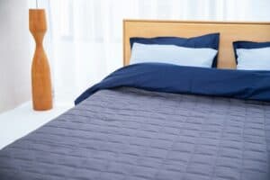 Cozy bed with navy bedding and pillows.