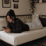 Person relaxing on daybed, using phone.