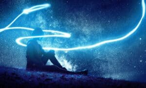 Person sitting under a starry sky.