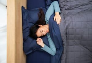 Woman sleeping under a weighted blanket.