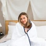 Woman smiling under a cozy blanket.