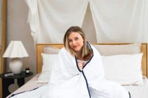 Woman smiling under a cozy blanket.