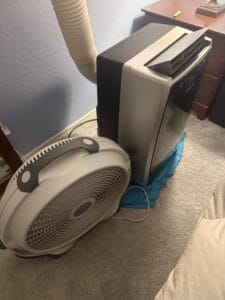 a bedside fan next to a portable AC unit in home
