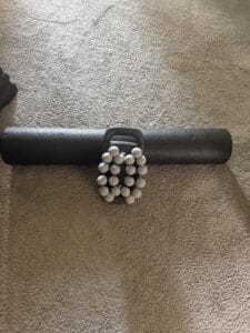 a massage gun next to a foam roller