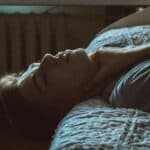 someone laying on a bed with neck pain