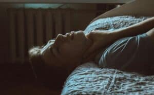 someone laying on a bed with neck pain