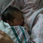 a swaddled baby in arms