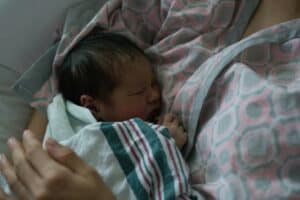 a swaddled baby in arms