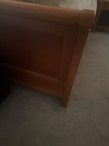 a wood bed frame in a bedroom setup