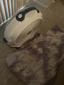a cooling blanket folded up in front of floor fan
