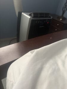 a portable ac in bedroom with corner of the bed