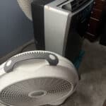 a portable ac unit and bedroom floor fan side by side