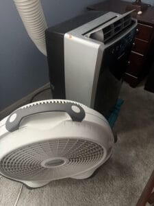 a portable ac unit and bedroom floor fan side by side