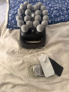 TENS unit with massage gun laying on bed